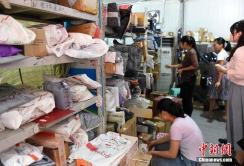 某高校快递点工作人员正忙碌着整理快递，向学生拨打电话让其尽快领取包裹。 周毅 摄