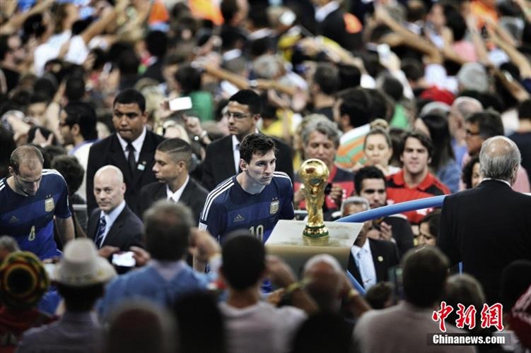 资料图：2014年巴西世界杯的决赛场内，梅西凝望着大力神杯。图片来源：视觉中国