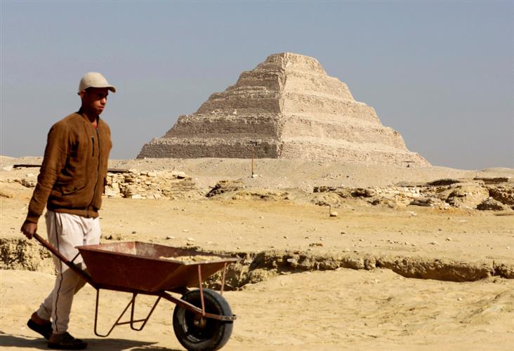 一名工人走在金字塔前。路透资料图