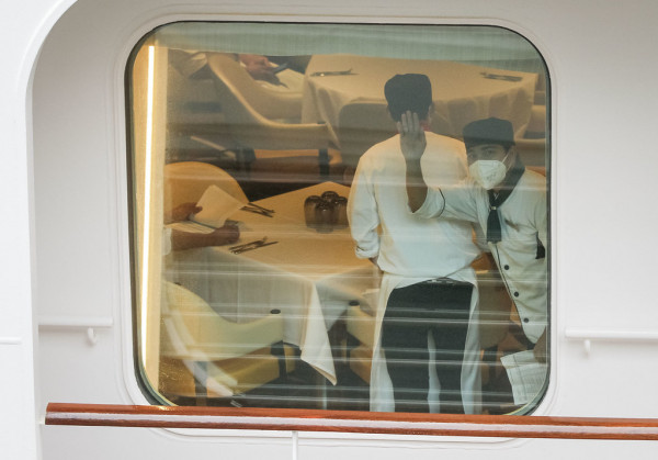 一名游轮员工向窗外途人挥手。